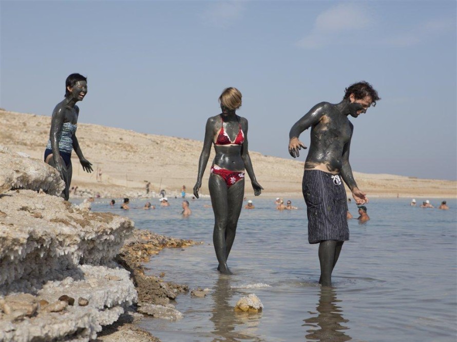 Tourists covered with mud, at a Dead Sea beach ​